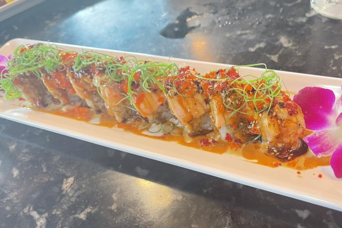 Baked sushi roll topped with scallions, roe and savory sauce