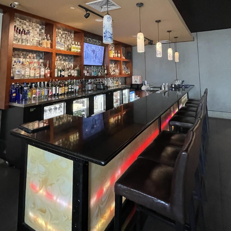 Well-stocked dark bar counter with hanging lamps at Sakura Sushi & Hibachi, a Japanese Restaurant in Kapolei