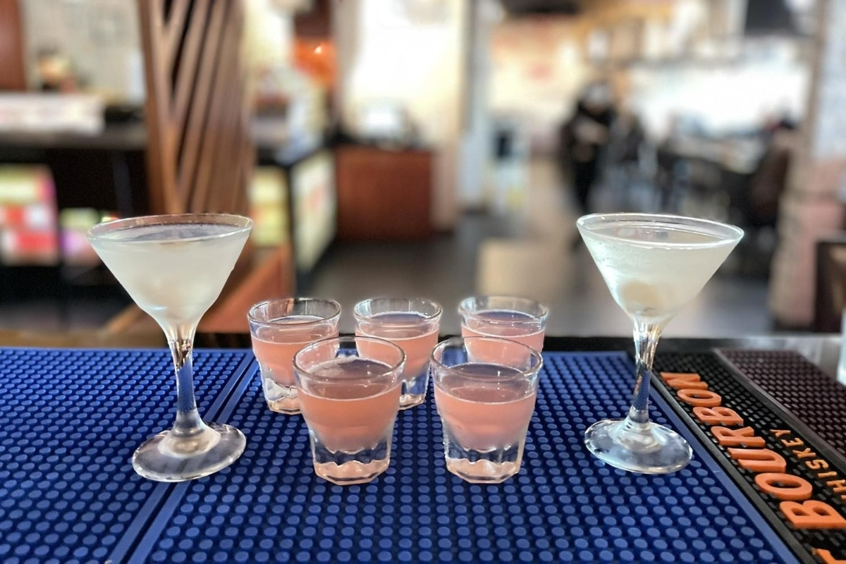 Cocktail glasses and pink shot drinks arranged on bar mat at Sakura Sushi & Hibachi, a Japanese Restaurant in Kapolei