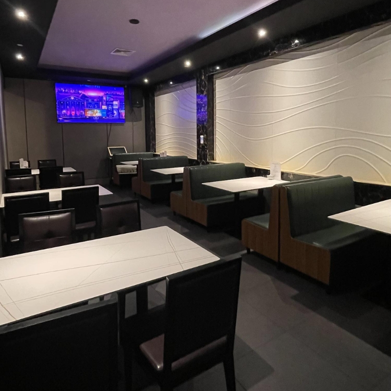 Dim dining area with booth seats and wall TV at Sakura Sushi & Hibachi, a Japanese Restaurant in Kapolei