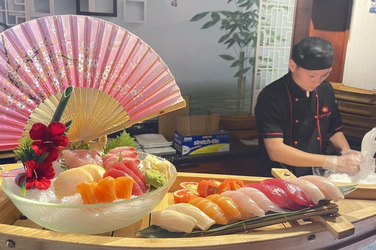 Luxury sushi sashimi boat platter with chef preparing food at Sakura Sushi & Hibachi, a Japanese Restaurant in Kapolei