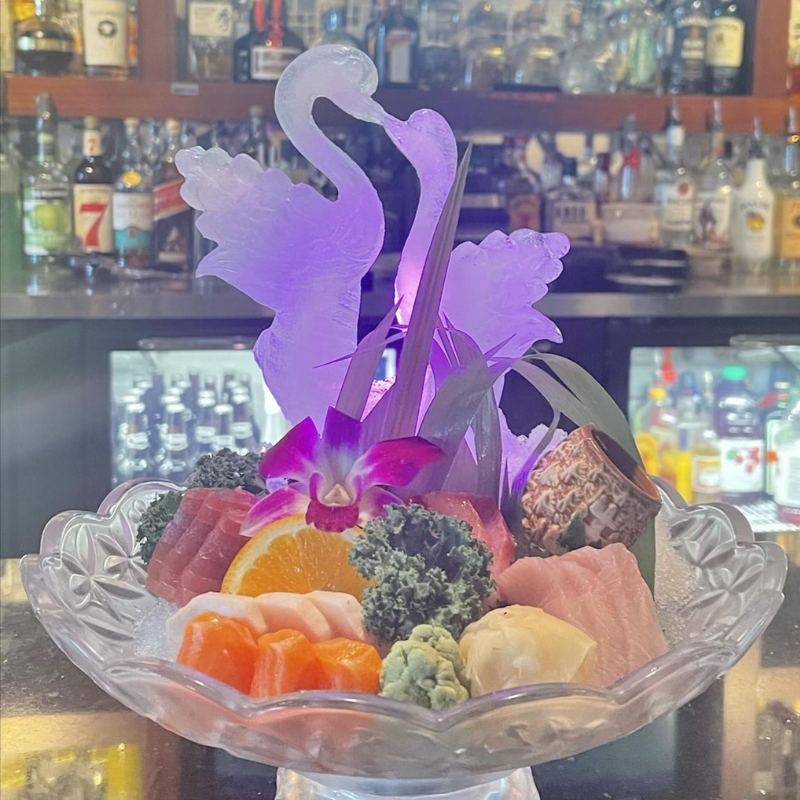 Premium sashimi platter with glowing swan ice carving at Sakura Sushi & Hibachi, a Japanese Restaurant in Kapolei
