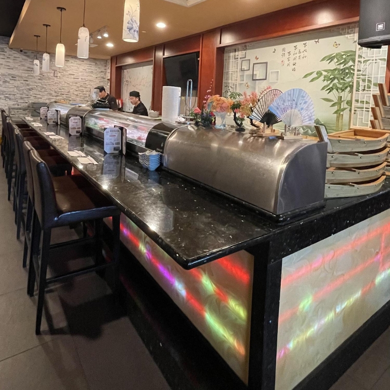 Sushi prep counter with chefs and decorative ornaments at Sakura Sushi & Hibachi, a Japanese Restaurant in Kapolei