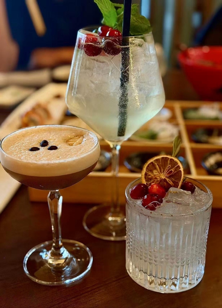 Assorted cocktails with cranberries and mint at Sapporo Izakaya, a Japanese Restaurant in The Woodlands