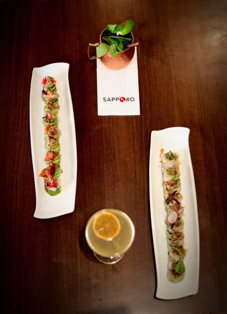 Sushi rolls and cocktails on a wooden table at Sapporo Izakaya, a Japanese Restaurant in The Woodlands