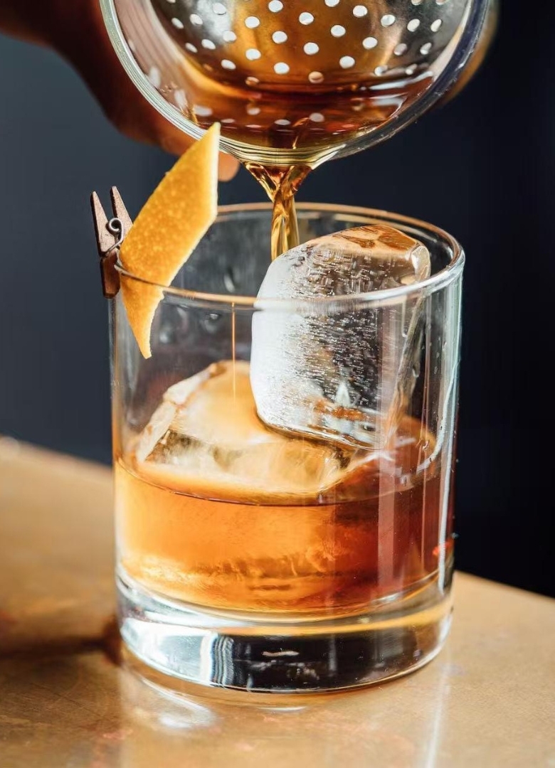 Whiskey cocktail with ice and orange garnish at Sapporo Izakaya, a Japanese Restaurant in The Woodlands