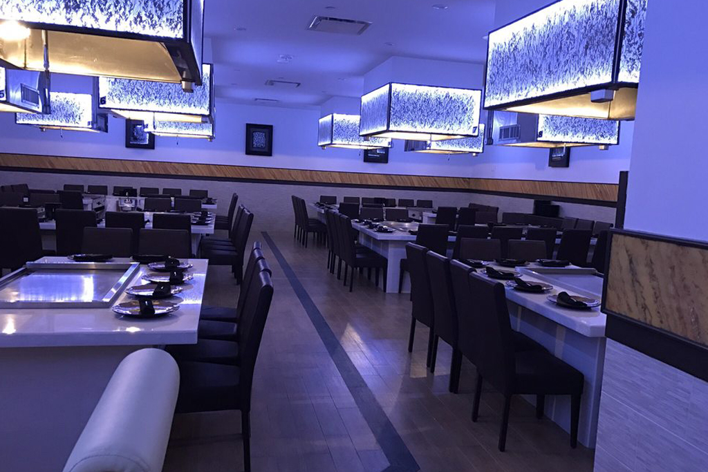 Neatly arranged tables and chairs in a blue-lit dining space at Sasa, a Japanese Restaurant in Farmingdale.