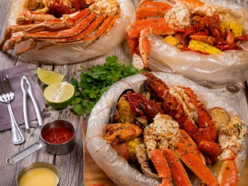 Cajun seafood boil bags with crab legs, lobster tails, corn, potatoes and dipping sauces at Seafood&wings, a Seafood Restaurant in Greenville
