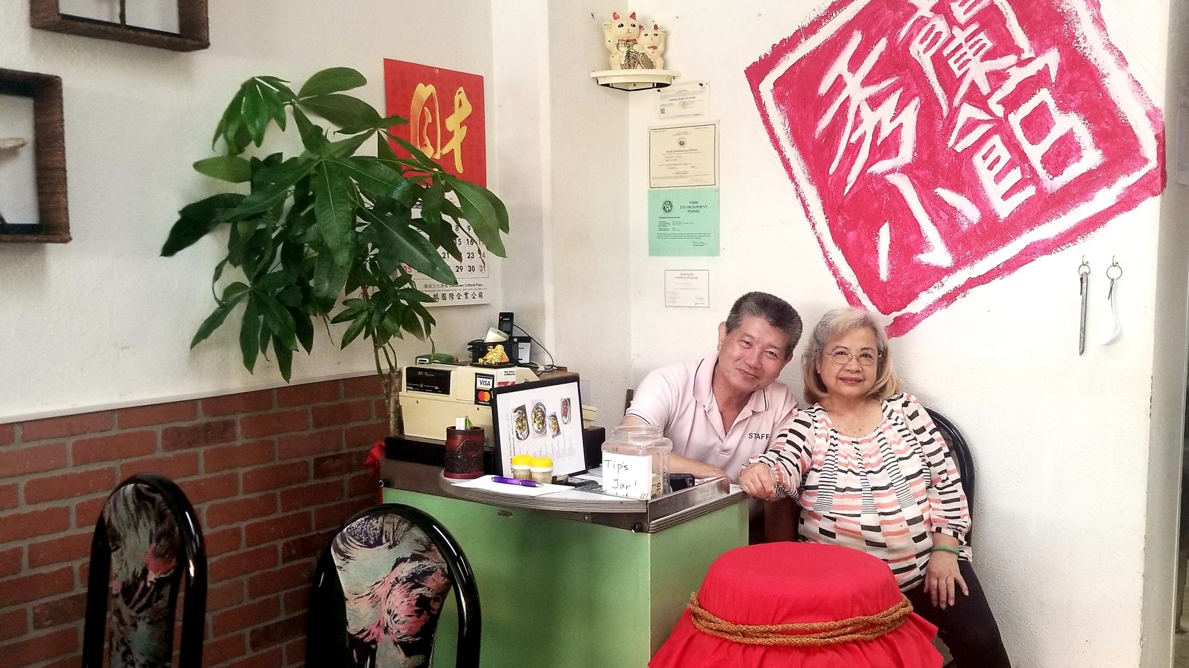 Two elders by the counter in Lanxiu Bistro, with the shop's sign on the wall