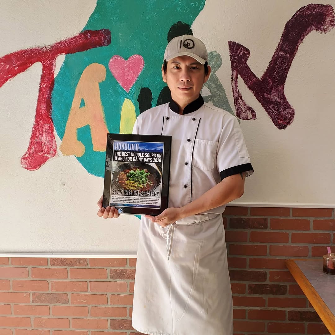 Chef holding 'Best Noodle Soups' plaque by Taiwan mural at Seasons Taiwanese Eatery，a Taiwanese Restaurant in Honolulu