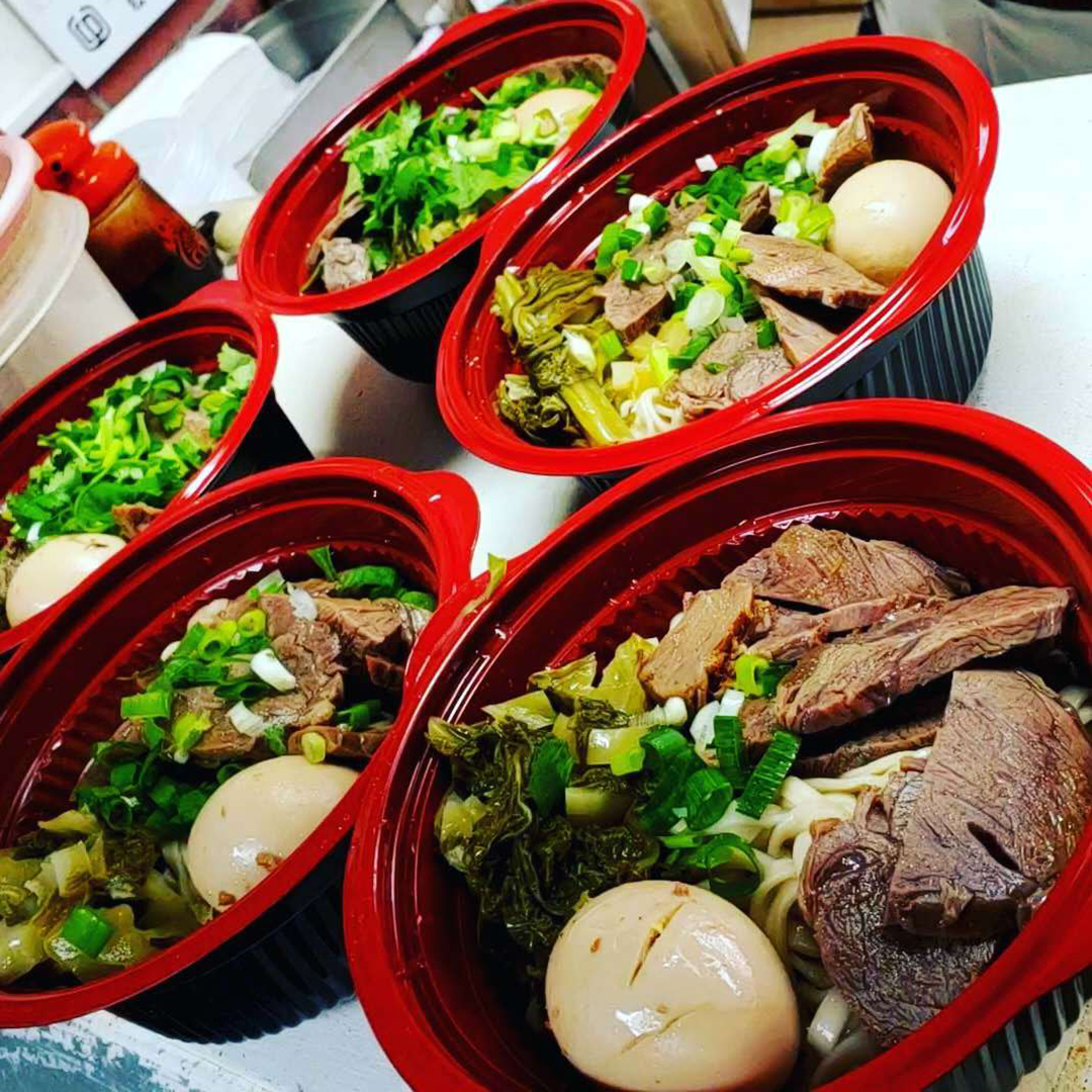 Seasons-Taiwanese-Eatery-Taiwanese-Restaurant-Beef-Noodle-Honolulu Several red - rimmed bowls filled with beef noodles, pickled vegetables, scallions and eggs at Seasons Taiwanese Eatery,a Taiwanese Restaurant in Honolulu