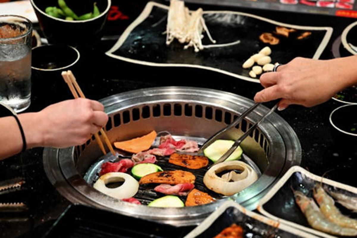 A Korean BBQ grill with various meats and vegetables being cooked at Seoul Korean BBQ & Hotpot，a Korean Restaurant in Mason