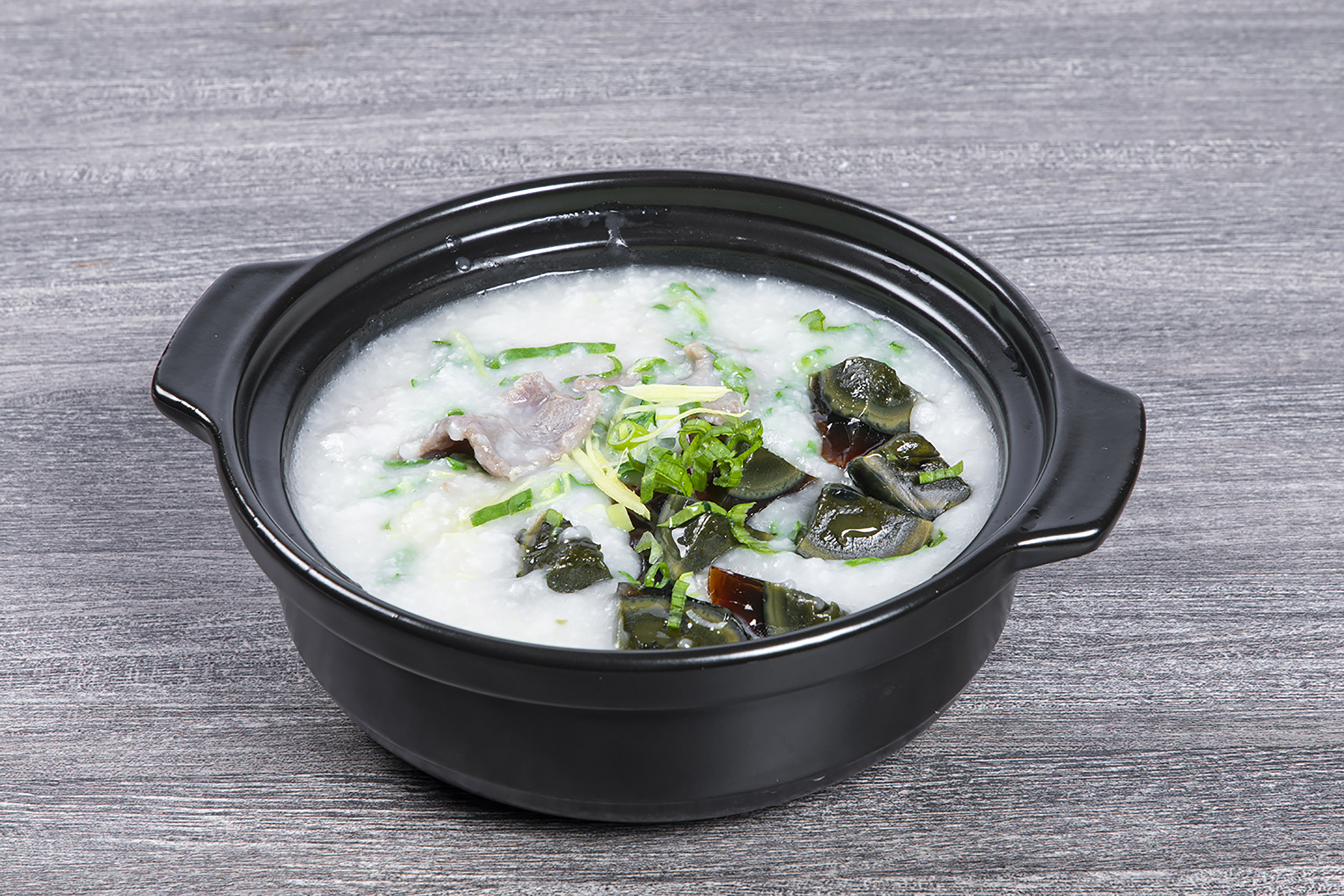 Century egg and lean pork congee garnished with fresh green onion at Shaxian Snacks, a Chinese Restaurant in Elmhurst
