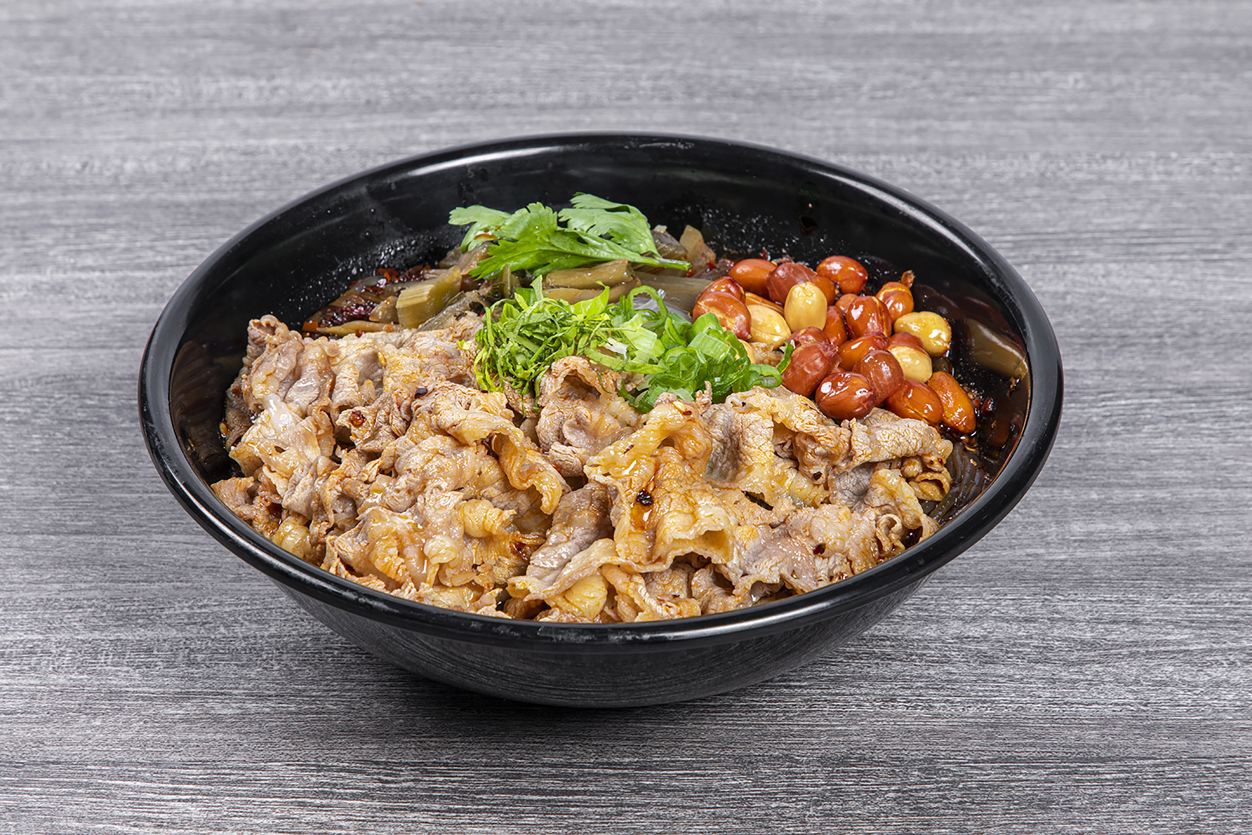 Spicy beef slice sour noodles topped with peanuts and cilantro at Shaxian Snacks, a Chinese Restaurant in Elmhurst