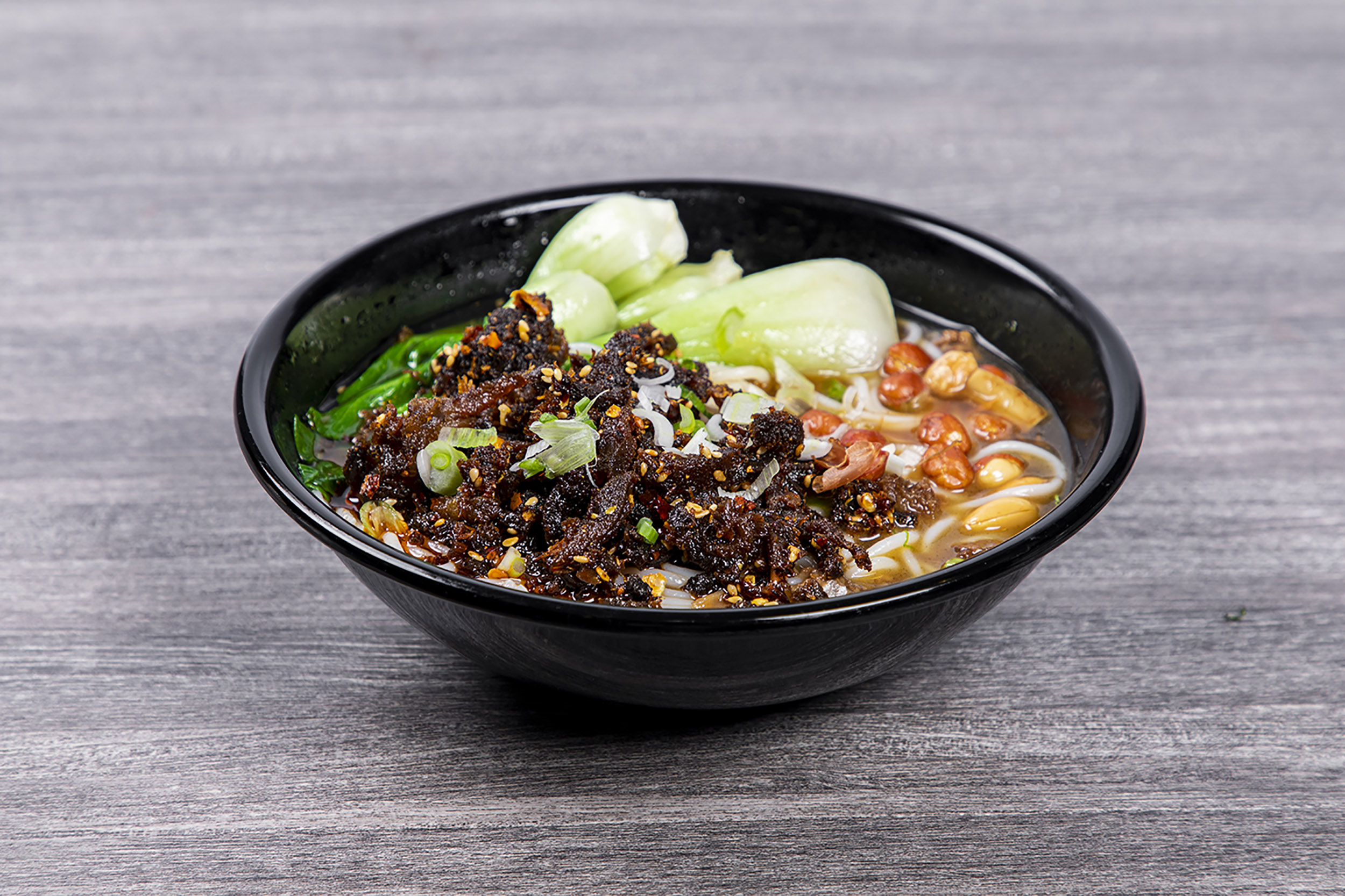 Spicy beef rice noodles with peanuts and green veggies at Shaxian Snacks, a Chinese Restaurant in Elmhurst