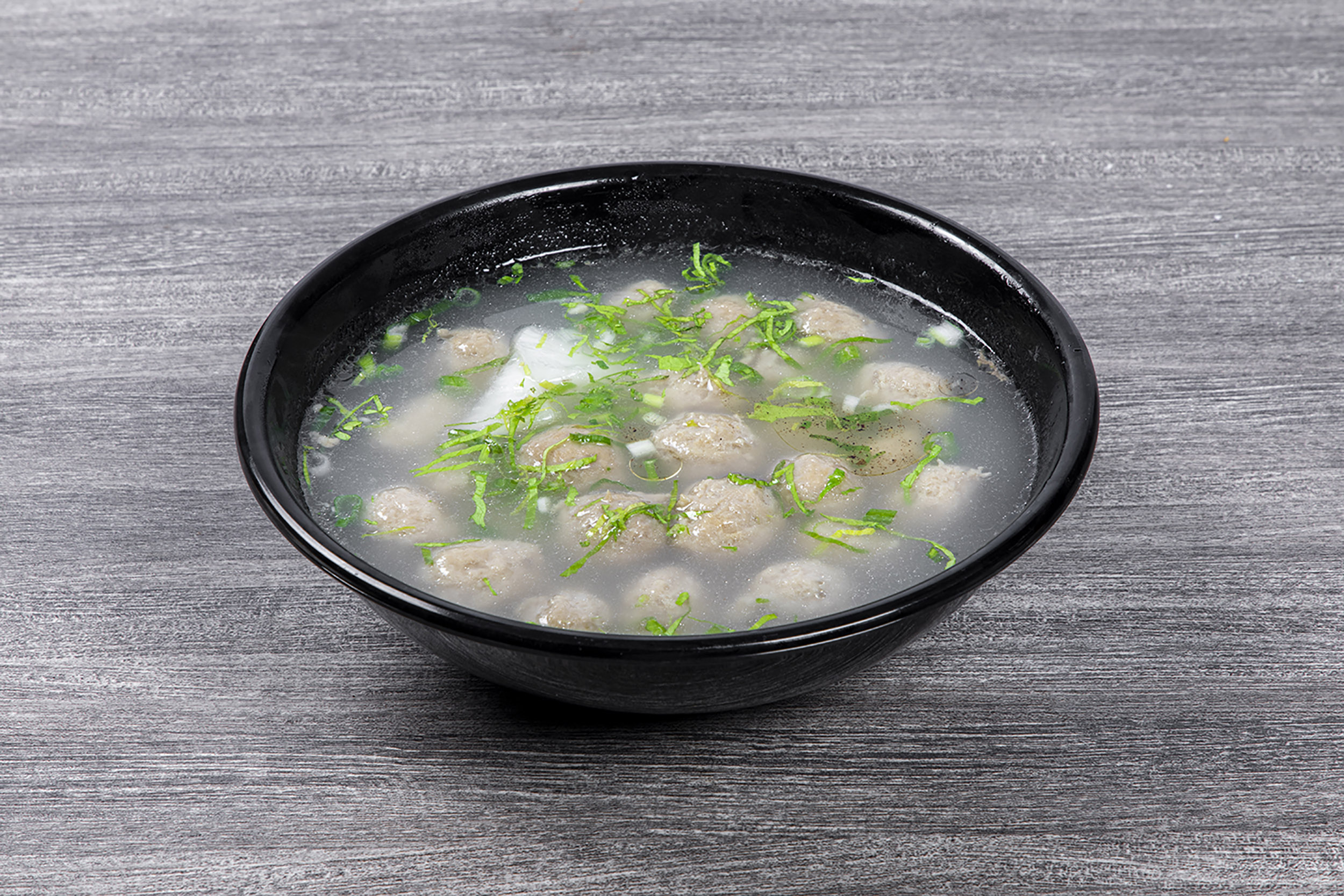 Clear pork meatball soup garnished with chopped green herbs at Shaxian Snacks, a Chinese Restaurant in Elmhurst
