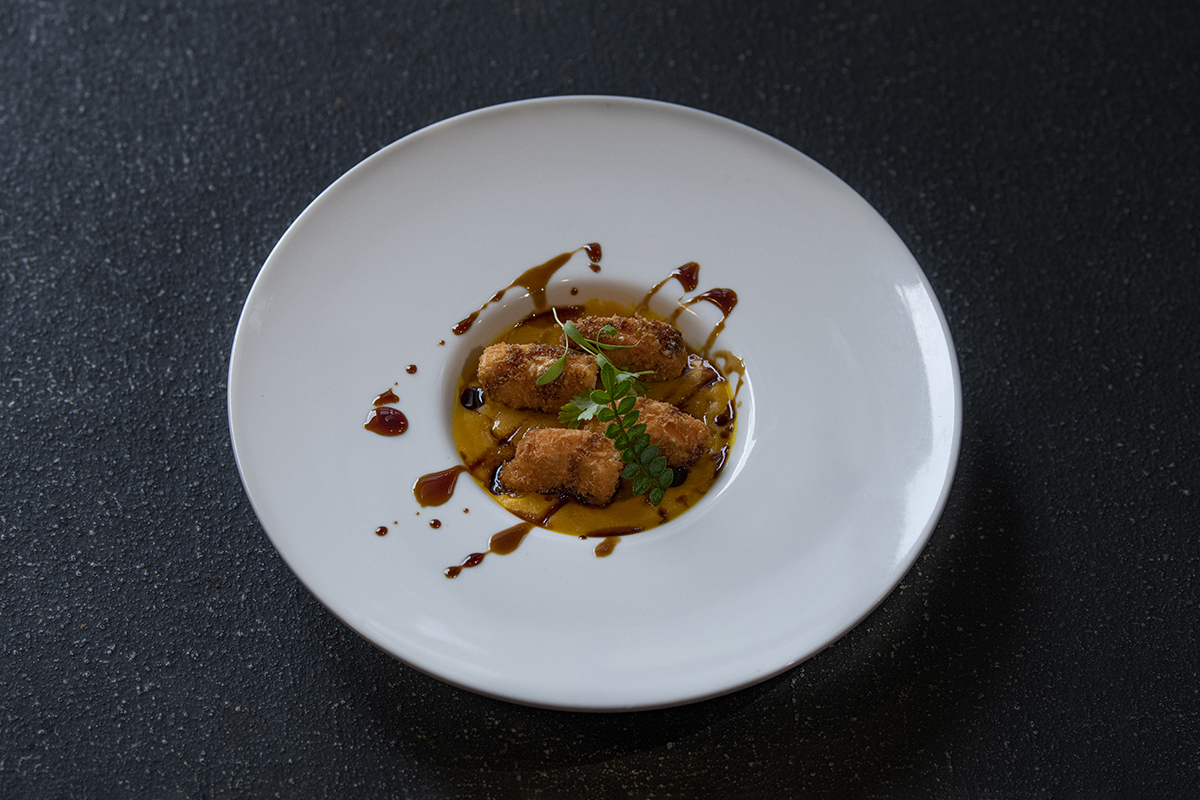 Crispy fried bites in a yellow sauce, garnished with herbs at Shiki Sushi，a Japanese Restaurant in Santa Rosa