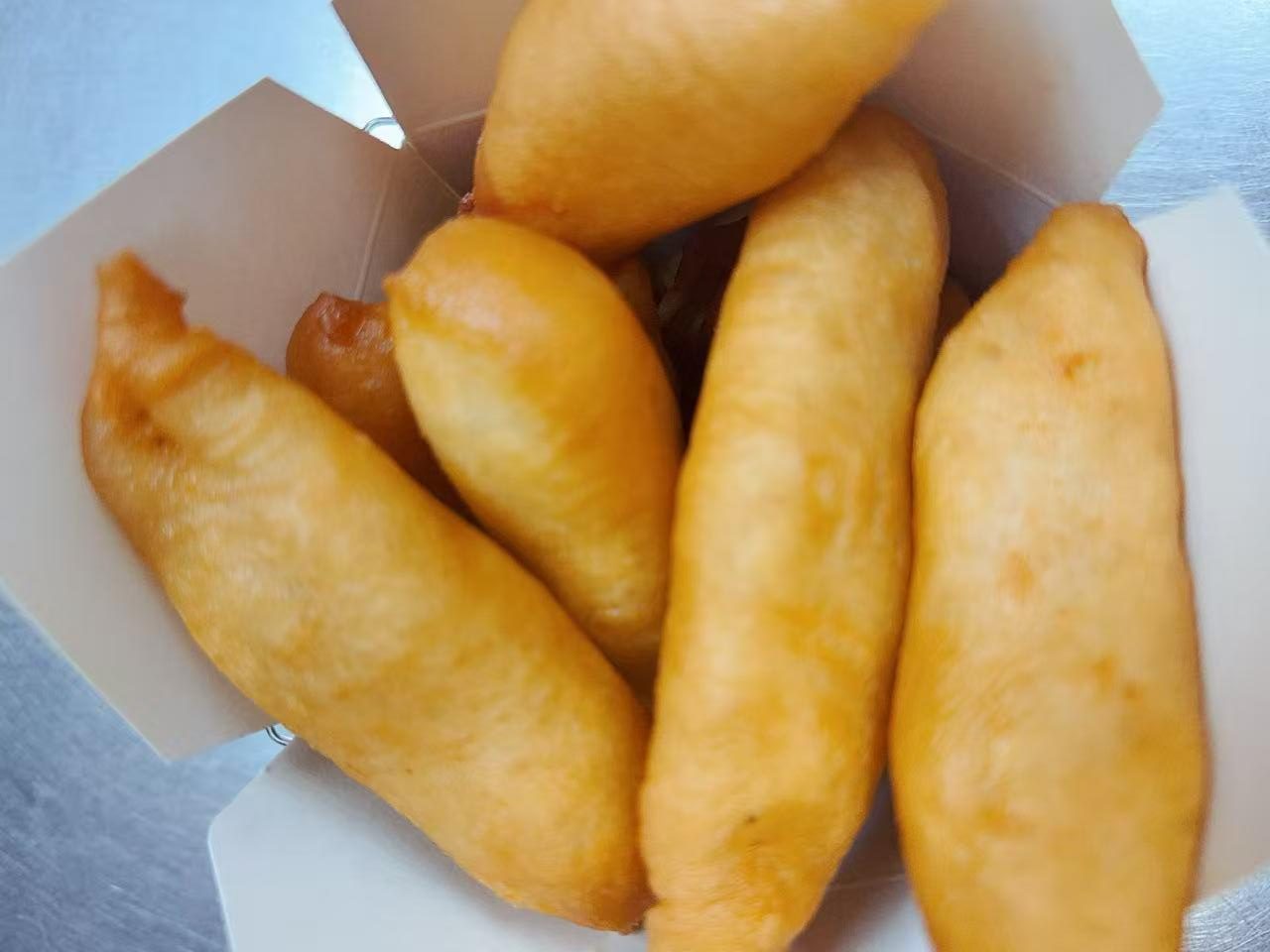Golden fried dough sticks packed inside white paper takeout box at Silk Road Bistro, a Chinese Restaurant in Martiborough