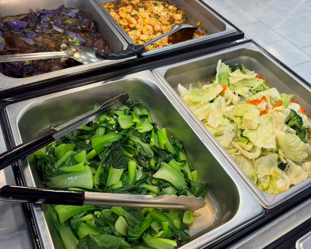 Multiple homemade vegetable dishes on buffet trays at Siu Lap City, a Chinese Restaurant in Houston