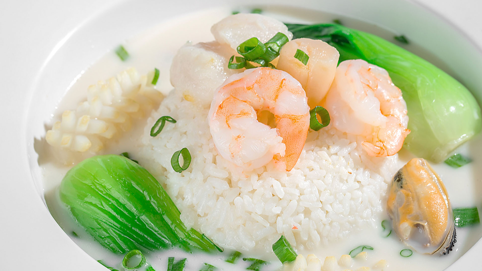 Creamy seafood congee with shrimp, mussels and fresh bok choy at Smile House Cafe, a Hong Kong Style Fast Food Restaurant in San Francisco