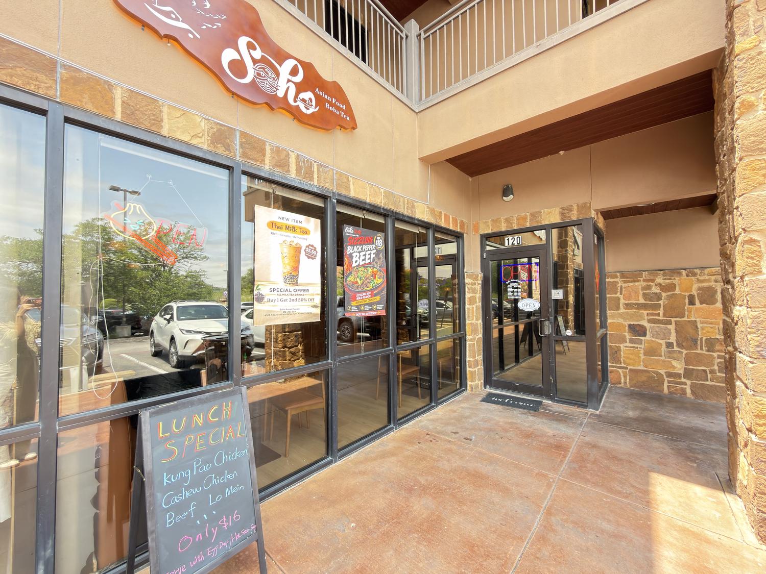 Exterior of SoHo Asian Fusion restaurant with stone facade, neon "OPEN" sign, and lunch specials at SoHo Asian Fusion, a Asian fusion restaurant in Austin