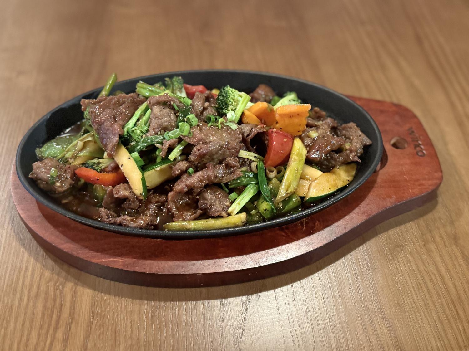 Sizzling beef stir-fry with mixed vegetables in a black iron skillet at SoHo Asian Fusion, a Asian fusion restaurant in Austin