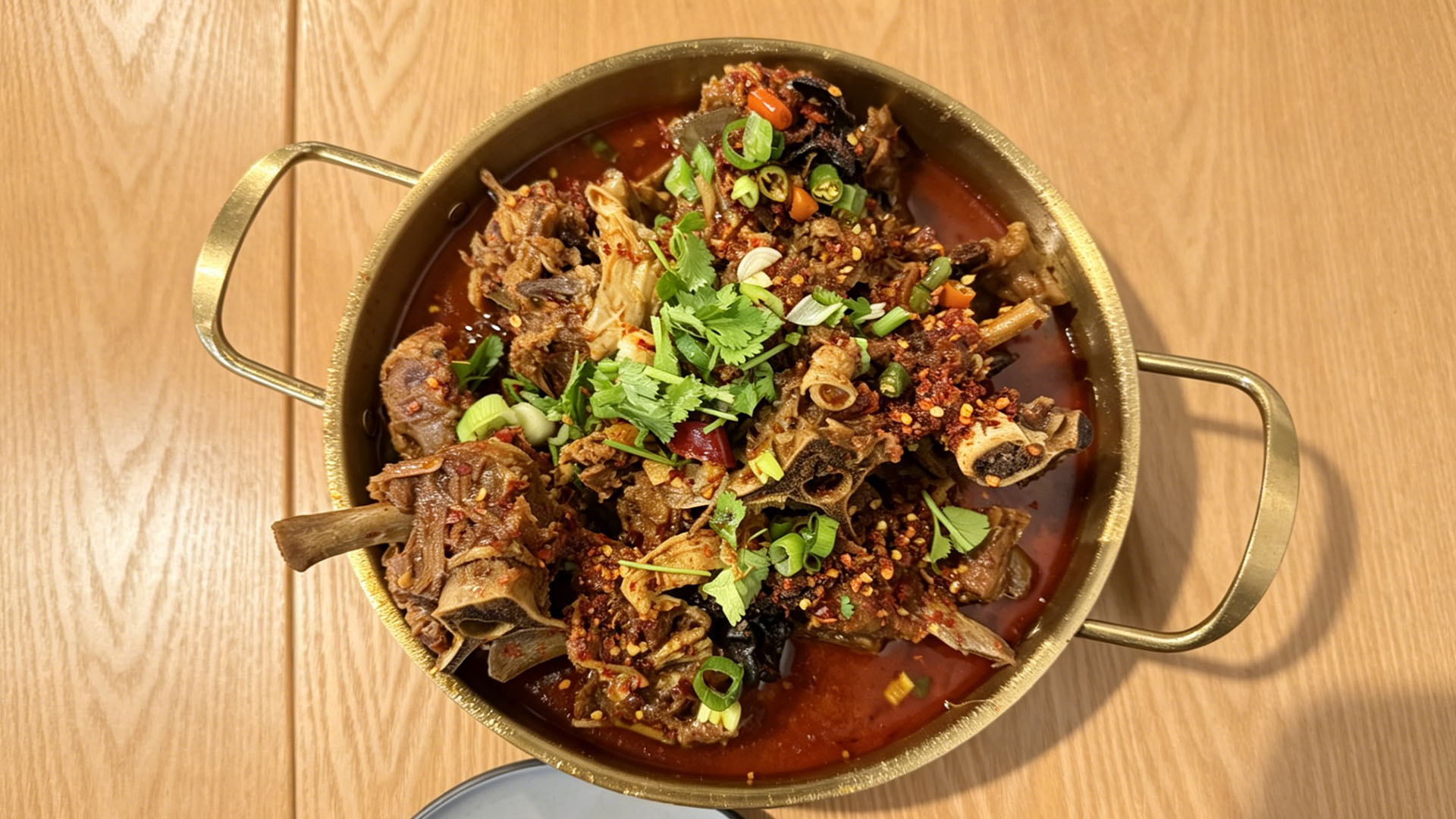 Spicy braised lamb spine hot pot with scallions and chili flakes at Spice House, a Chinese Restaurant in Plano