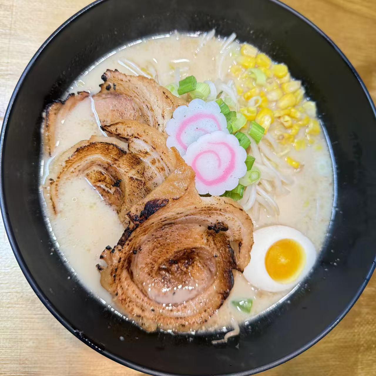 Pork belly ramen with corn, soft - boiled egg and decorative radish at Starbelly Asian Kitchen, a Asian Fusion Restaurant in Montclair
