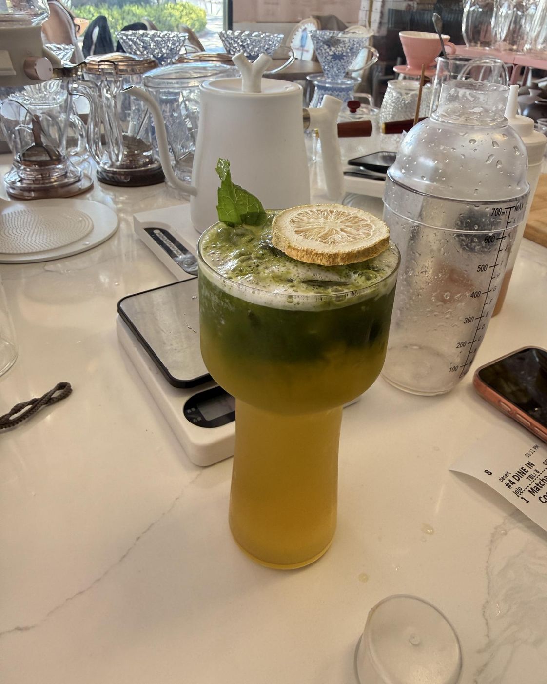 Iced matcha drink in a tall glass with dried lemon and mint