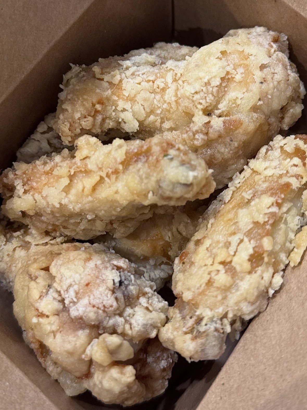 Crispy battered fried chicken wings inside paper takeout box at SunLite Eatery，an Asian Fusion Restaurant in Rochester