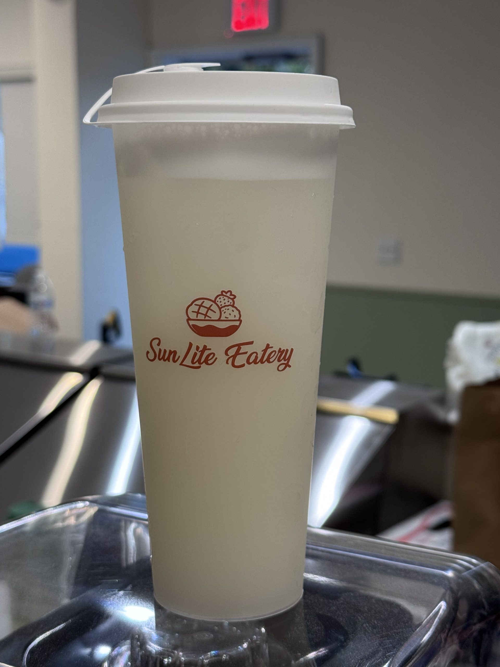 Pale milky iced beverage in branded SunLite Eatery tall plastic cup at SunLite Eatery，an Asian Fusion Restaurant in Rochester
