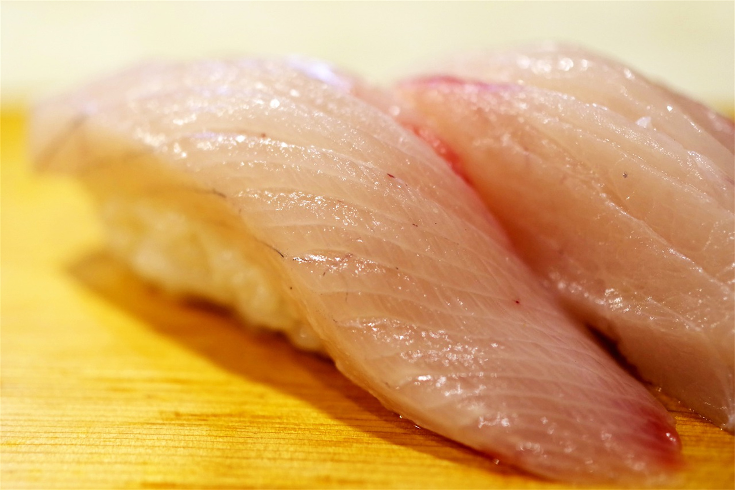Close-up of two fresh white fish nigiri sushi pieces served over hand-pressed sushi rice