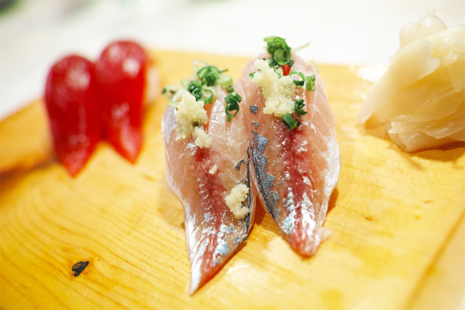 Fresh aji horse mackerel nigiri sushi topped with grated ginger and chopped green onions