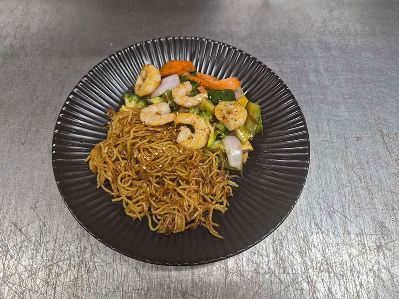 Shrimp chow mein stir-fried with mixed fresh vegetables on black plate at Sushi & Grill, a Asian Restaurant in Elkton
