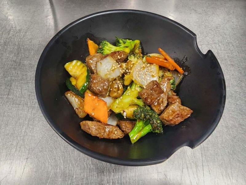 Stir-fried beef cubes with broccoli, squash and onion in a black bowl at New Asian & Sushi Bistro, a Asian Restaurant in Elkton