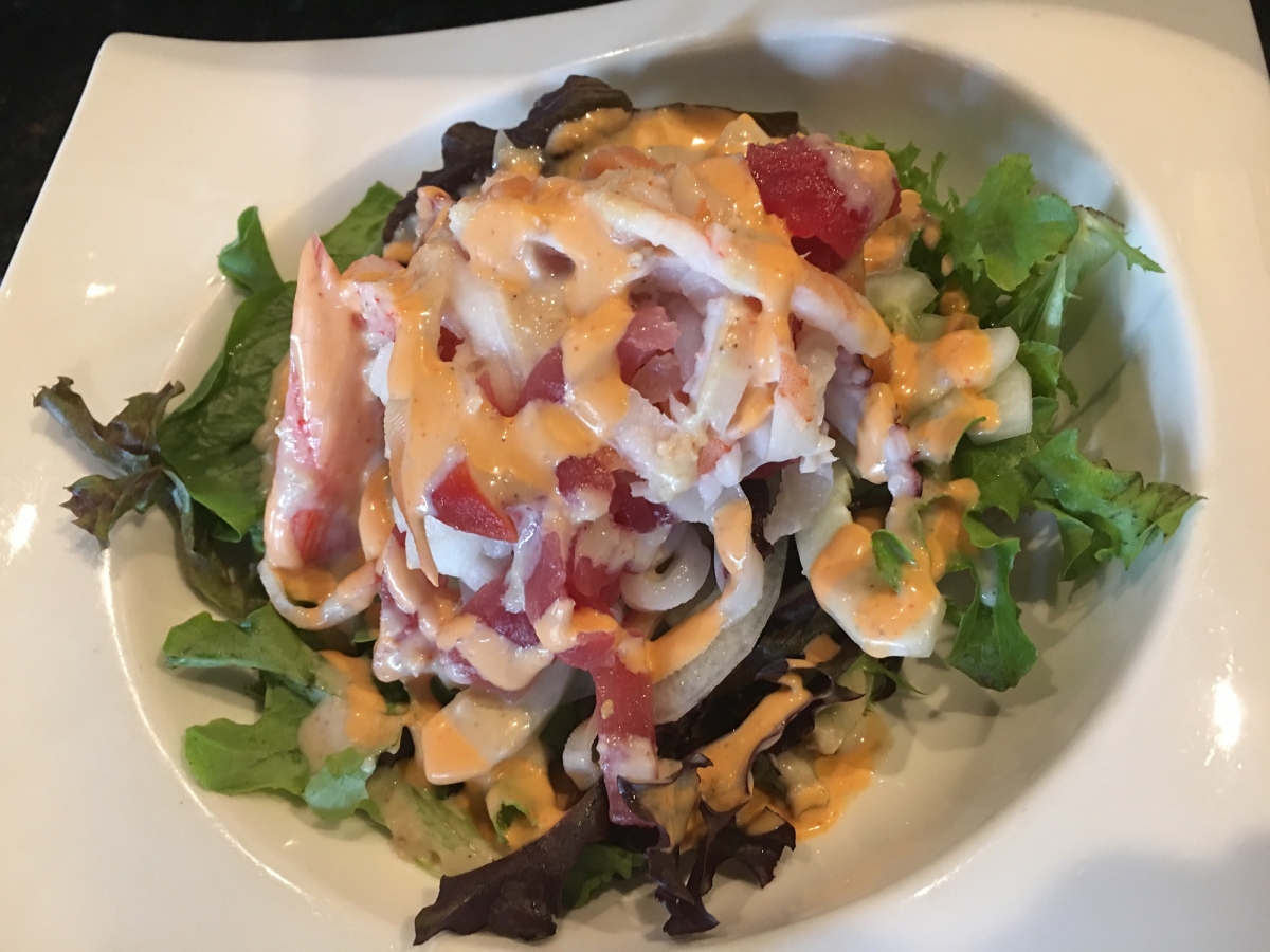 Seafood salad mixed with fresh greens and creamy spicy sauce in a white bowl at Sakura house, a Japanese Restaurant in Willow Grove
