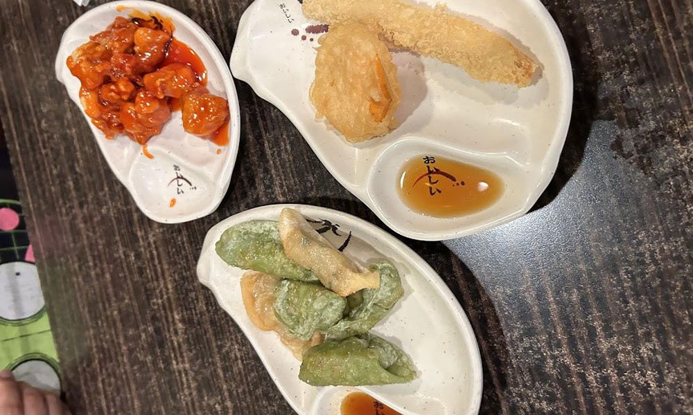 Three small white ceramic plates holding sweet sour chicken, tempura veggies and colorful fried dumplings with dipping sauces at Sushi & king seafood , a Sushi Restaurant in Commack