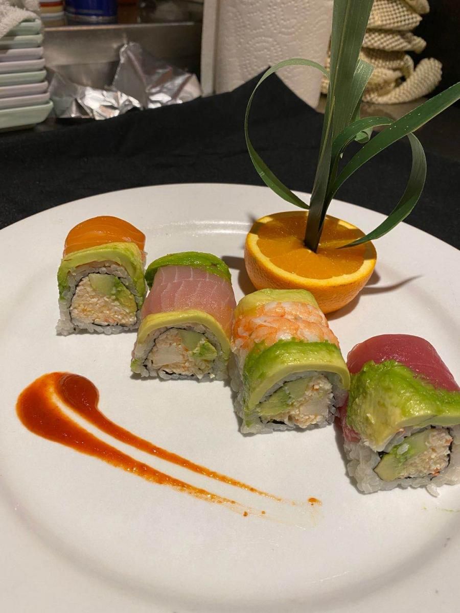 Colorful sushi roll platter on white plate with orange garnish