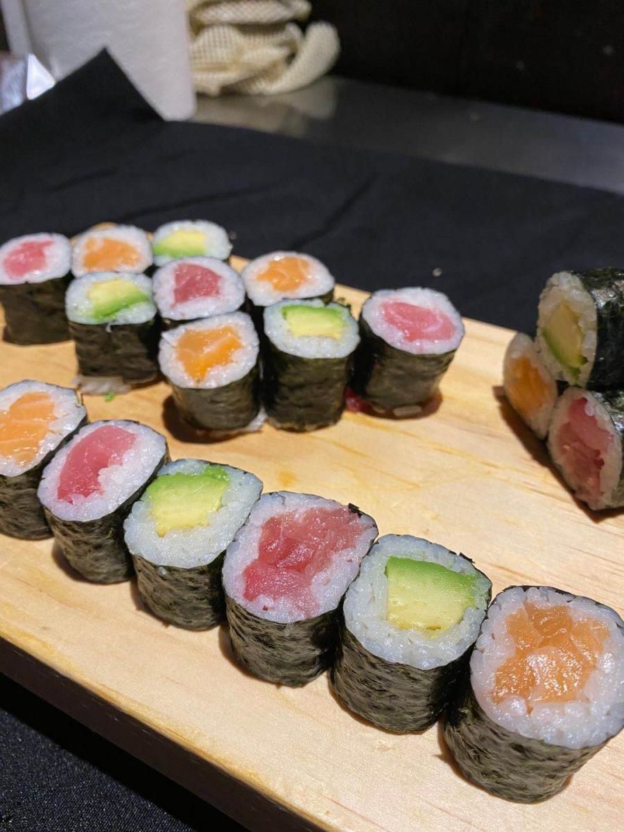 Maki sushi rolls with salmon, tuna and avocado on wooden board