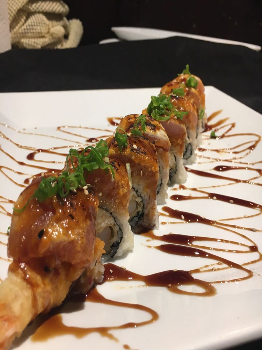 Seared sushi rolls on white plate with teriyaki sauce and green onion