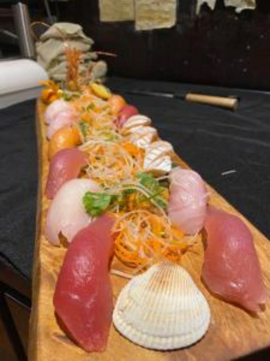 Assorted sashimi platter on long wooden board with garnishes
