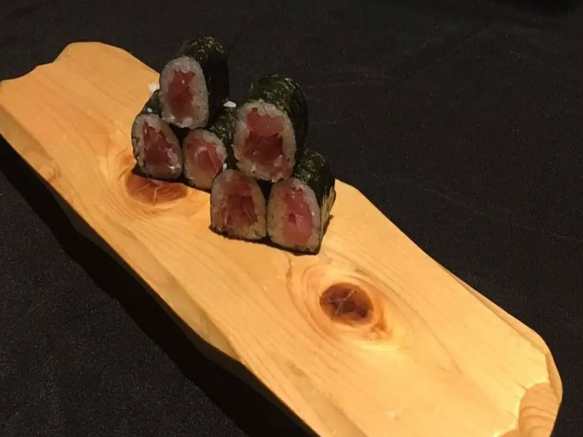 Tuna maki sushi rolls stacked on natural wooden plank