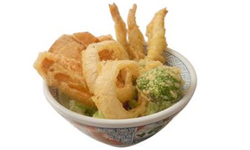 Mixed tempura with shrimp, onion rings and broccoli served in decorated Japanese ceramic bowl over lettuce, white background.
