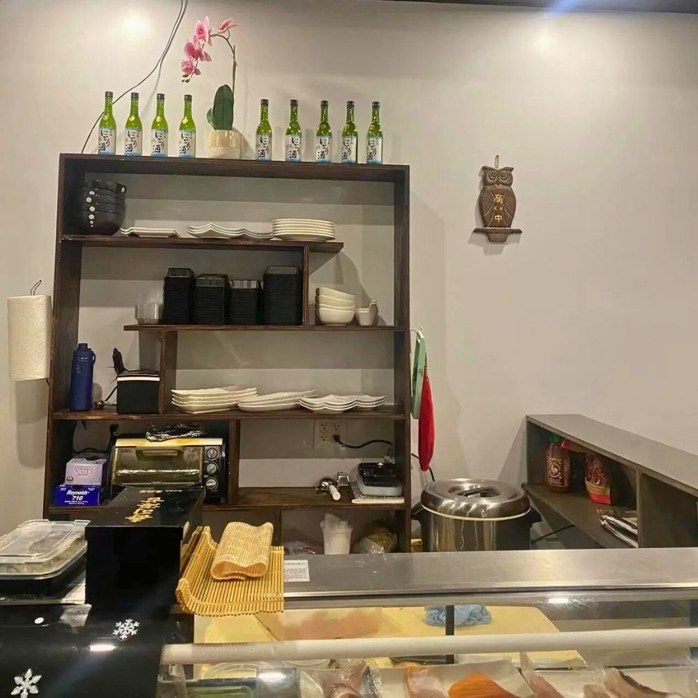 Kitchen prep area with shelves, plates, and sake bottles at Sushi of Miso, a Japanese Restaurant in Long Island City.