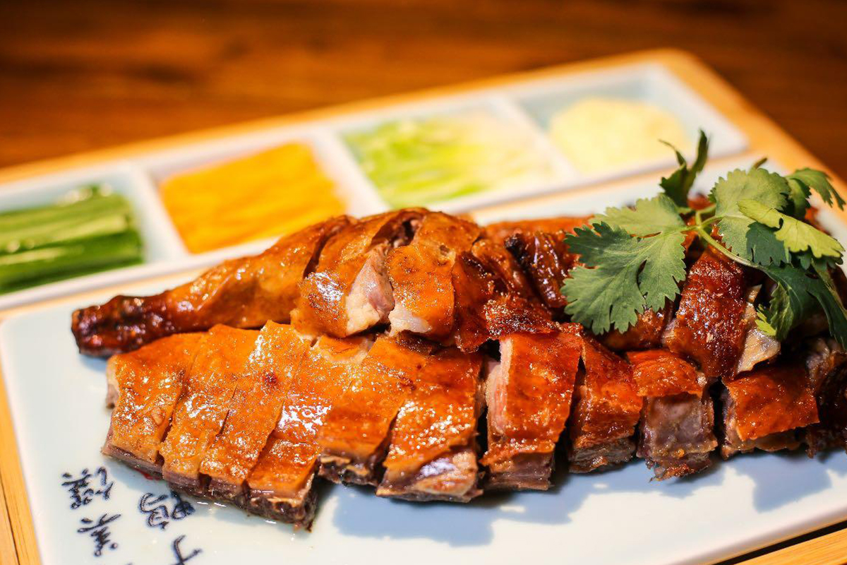 Sliced roast duck with colorful vegetable side dishes, garnished with cilantro at Szechuan Gourmet, a Chinese restaurant in New York
