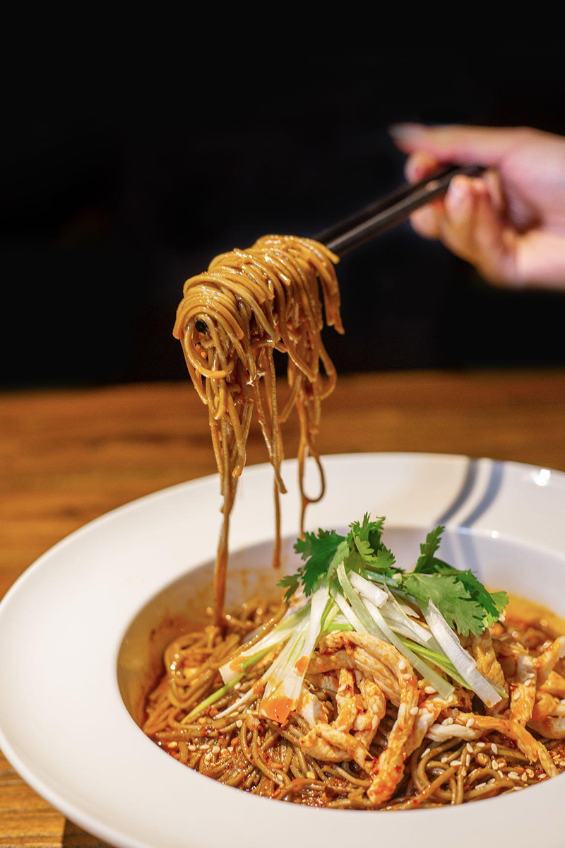 Noodles picked up by chopsticks, with cilantro and shredded scallions at Szechuan Gourmet, a Chinese restaurant in New York