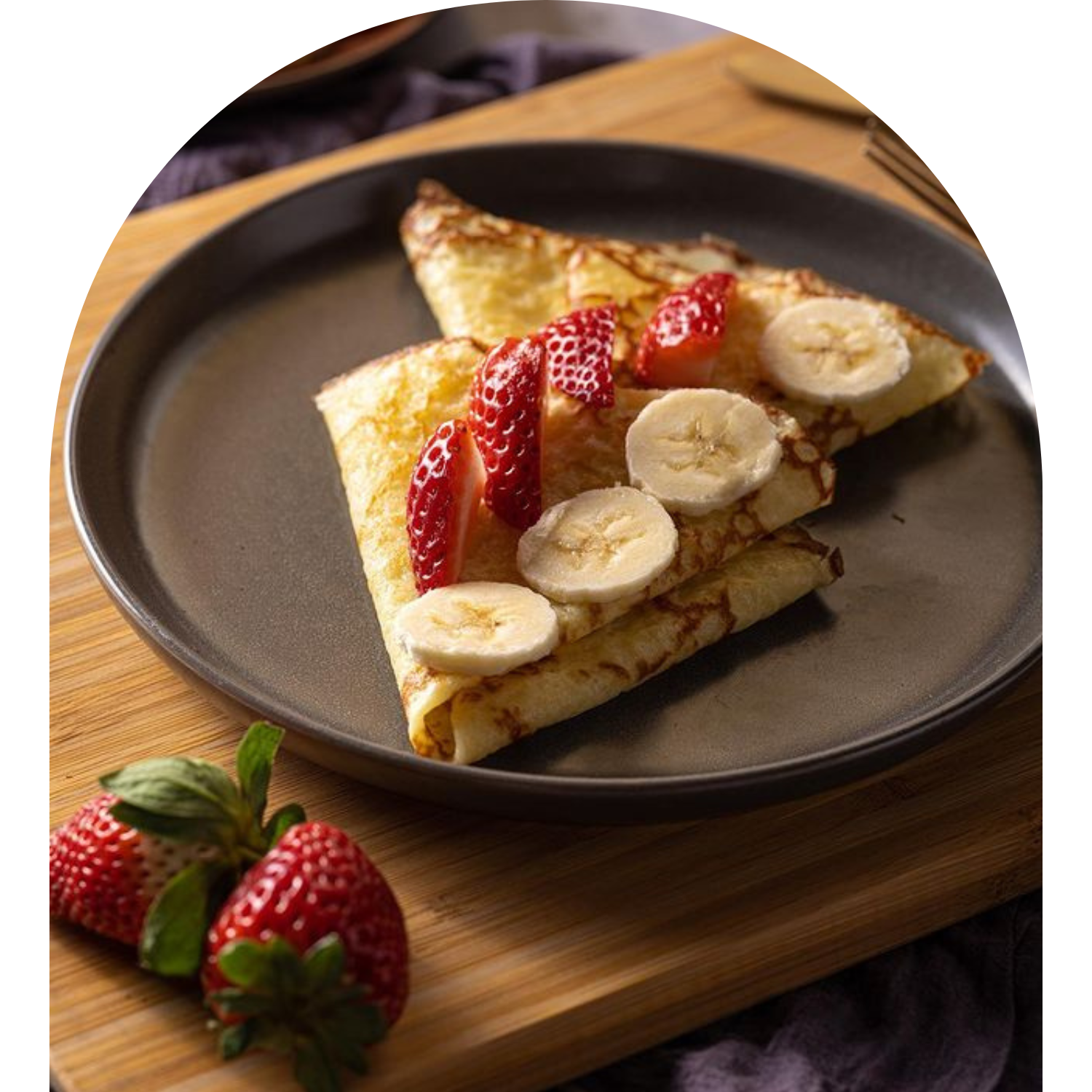 A black plate holds stacked fruit crepes, decorated with strawberry slices and banana slices on the surface at T-Swirl Crêpe，a Japanese Crêperie & Bubble Tea Shop in Phoenixville