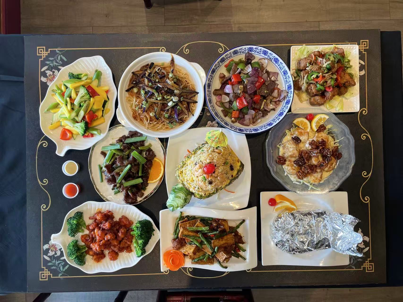 A full table of assorted Chinese fusion dishes on a decorated black table.