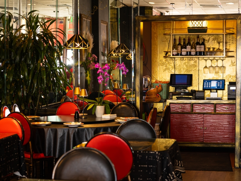 Restaurant bar and round table area decorated with orchids and greenery