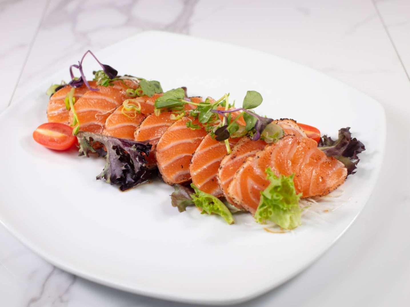 Fresh sliced salmon sashimi garnished with greens & cherry tomato at Taki Sushi, a Japanese Restaurant in Toronto